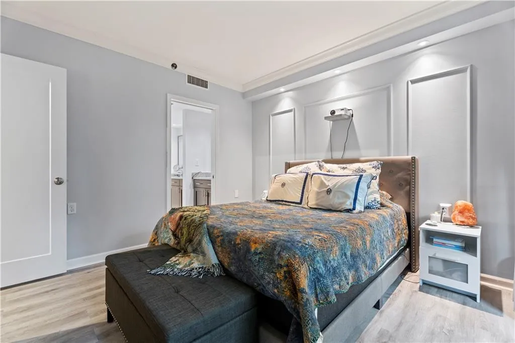 Bedroom with crown molding, wood finished floors, and connected bathroom