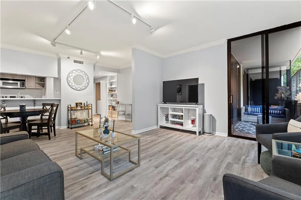 Living area with ornamental molding, track lighting, and light wood finished floors