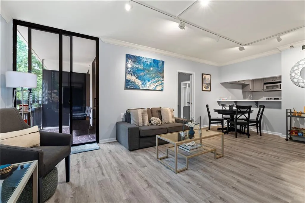 Living room featuring track lighting, crown molding, expansive windows, and light wood finished floors