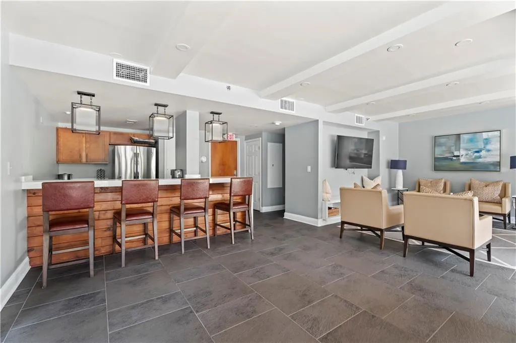 Kitchen featuring brown cabinetry, beam ceiling, a breakfast bar, freestanding refrigerator, and light countertops