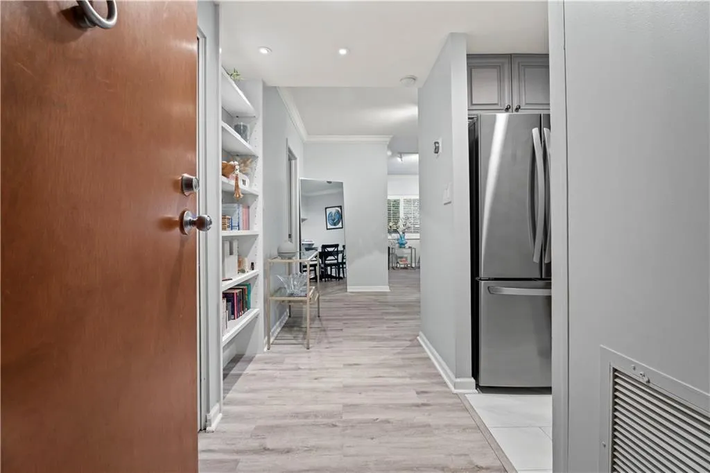 Hallway with ornamental molding and light wood-style floors