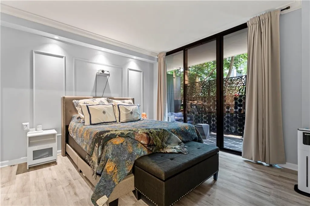 Bedroom with access to outside, wood finished floors, a wall of windows, and crown molding