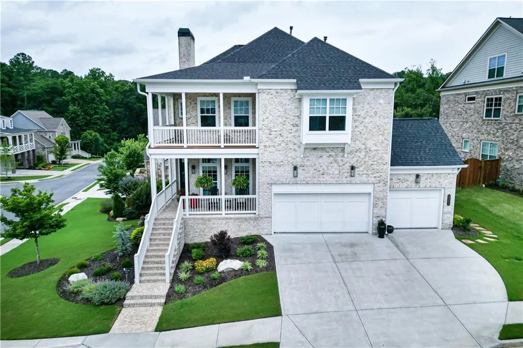 View of front of property with a porch, a chimney, a balcony, concrete driveway, and a garage