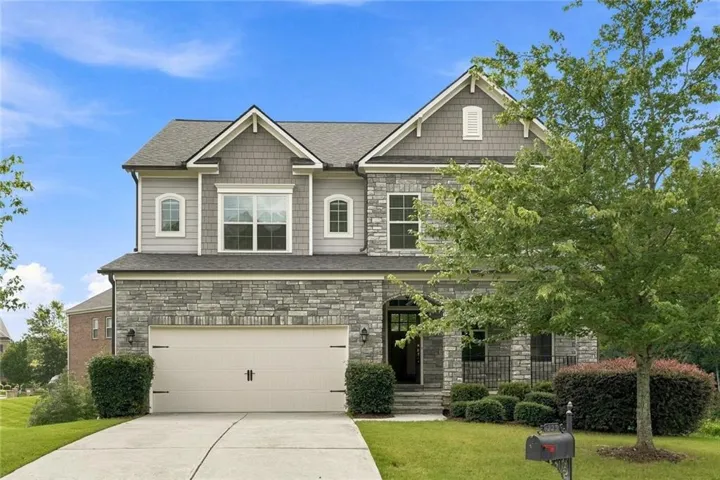 Two-story residence featuring a stone and siding exterior, an attached two-car garage, and a concrete driveway