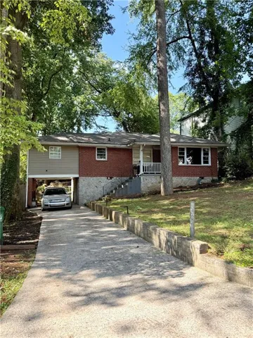 Brick and siding exterior residence featuring a concrete driveway, two-car carport, and mature trees