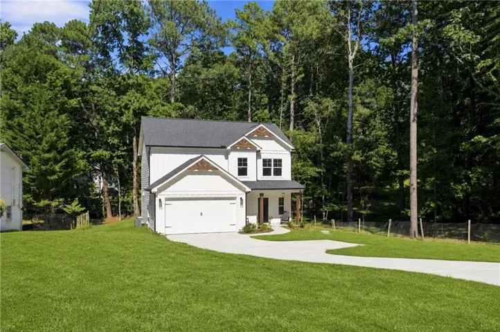 Two-story residence with white siding and dark roof shingles, featuring an attached two-car garage