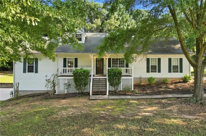 White siding exterior with dark green shutters, a welcoming front porch with white railings, and a dormer window