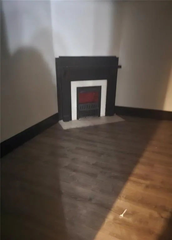 Unfurnished living room with a fireplace with flush hearth and dark wood finished floors