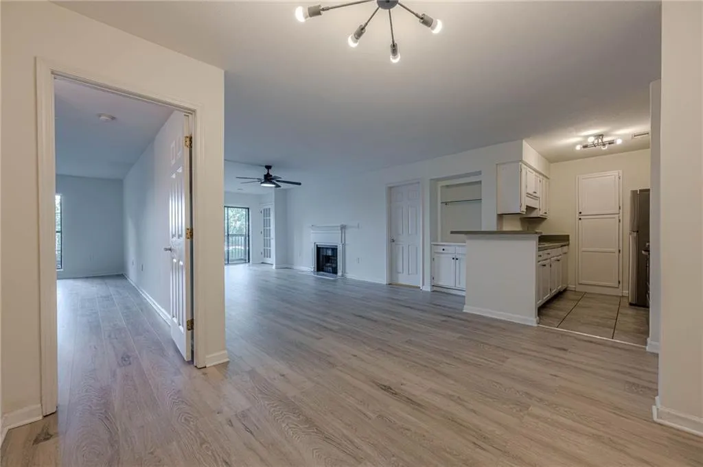 Unfurnished living room featuring light wood-style floors, a fireplace, ceiling fan, and a chandelier