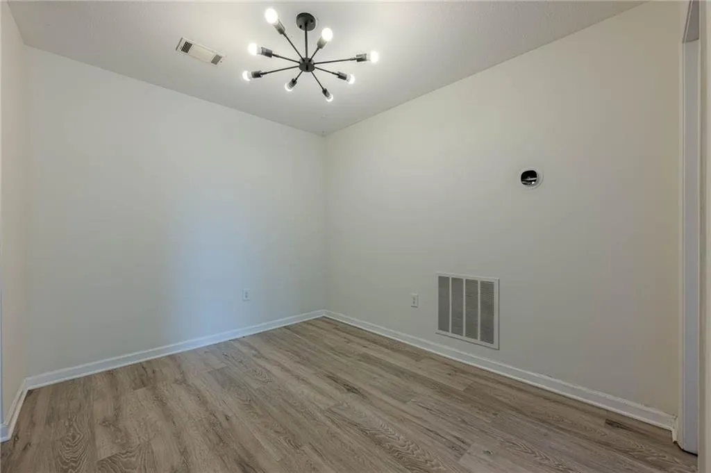 Empty room with light wood finished floors and a chandelier