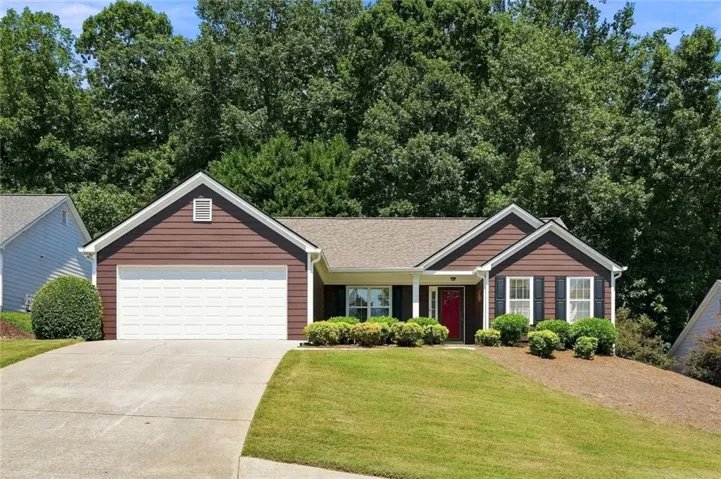 Brown siding exterior with white trim, a gabled roof, and a red front door