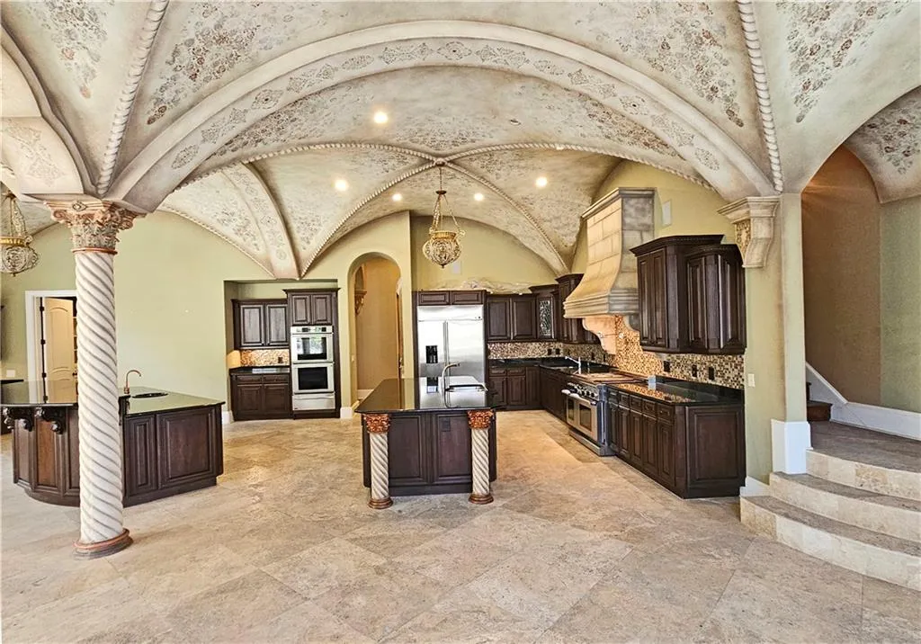 Kitchen with tasteful backsplash, appliances with stainless steel finishes, a kitchen breakfast bar, a kitchen island with sink, and lofted ceiling