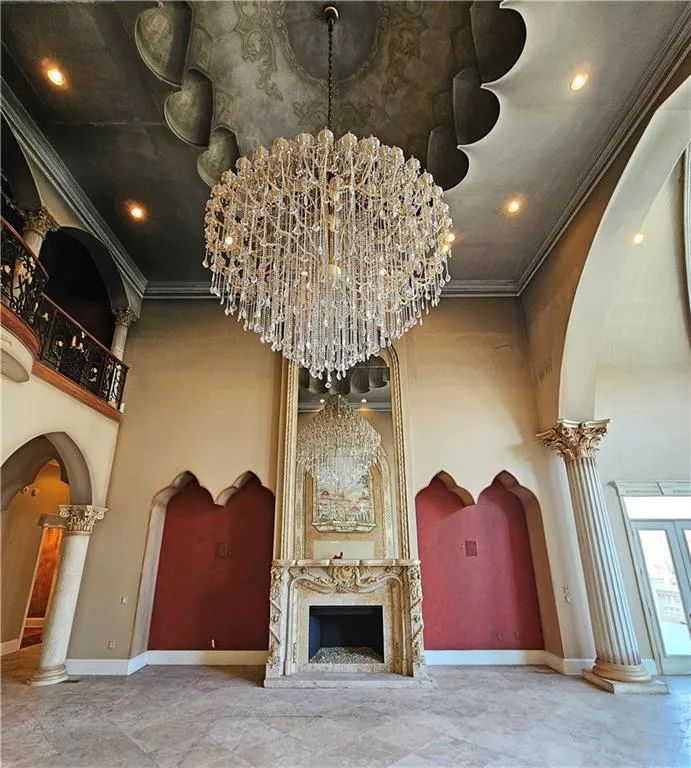 Room details with an inviting chandelier, crown molding, light tile floors, and decorative columns