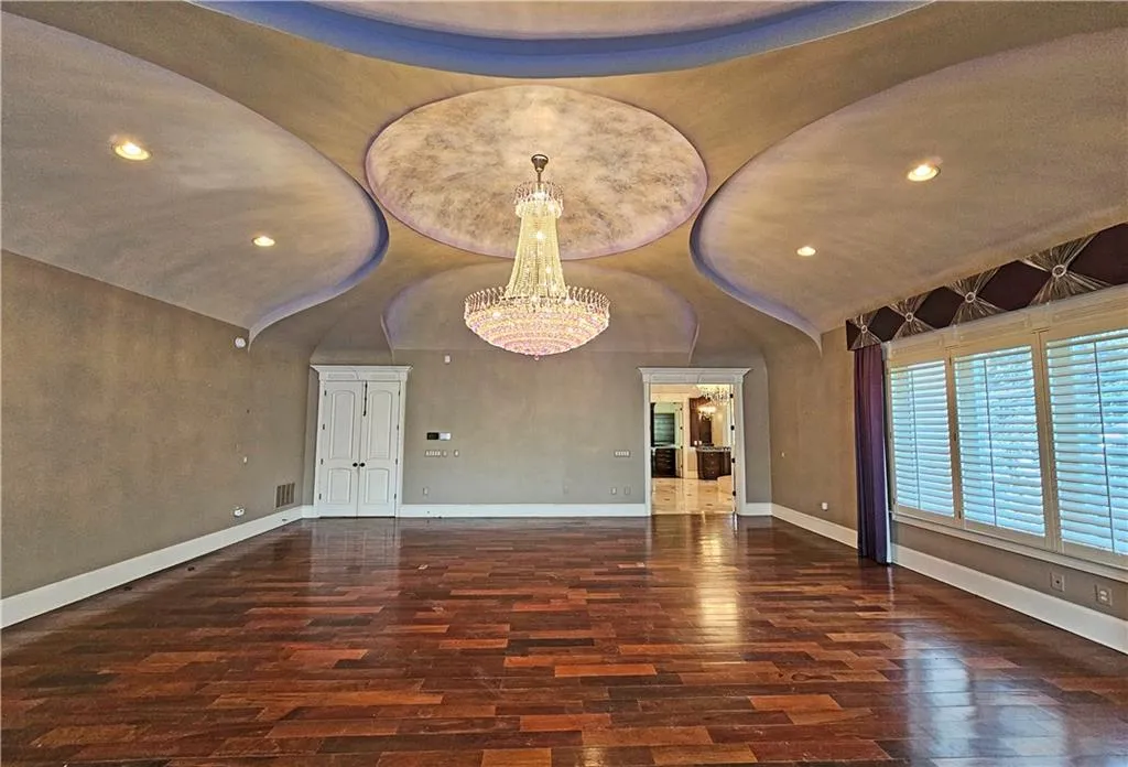 Empty room with a notable chandelier, lofted ceiling, and dark hardwood / wood-style flooring