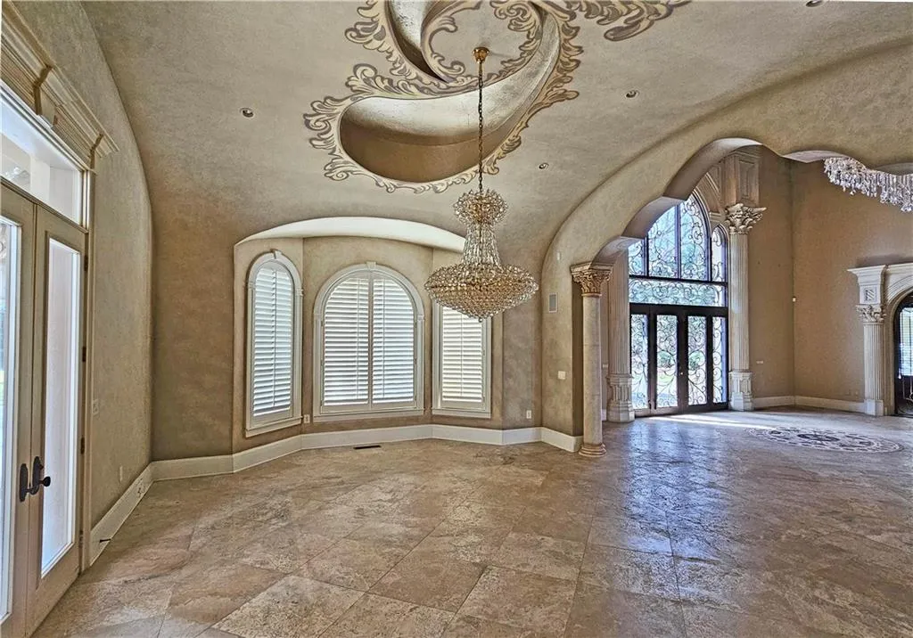Tiled foyer featuring plenty of natural light, french doors, a chandelier, and decorative columns