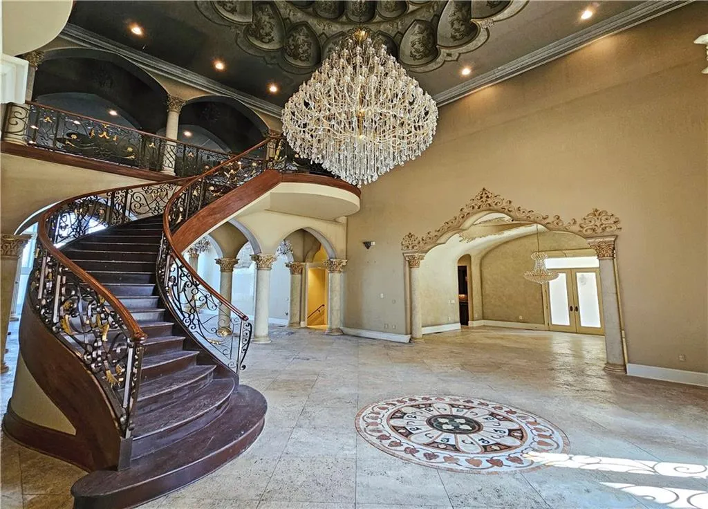 Foyer with a notable chandelier, light tile floors, a towering ceiling, and decorative columns