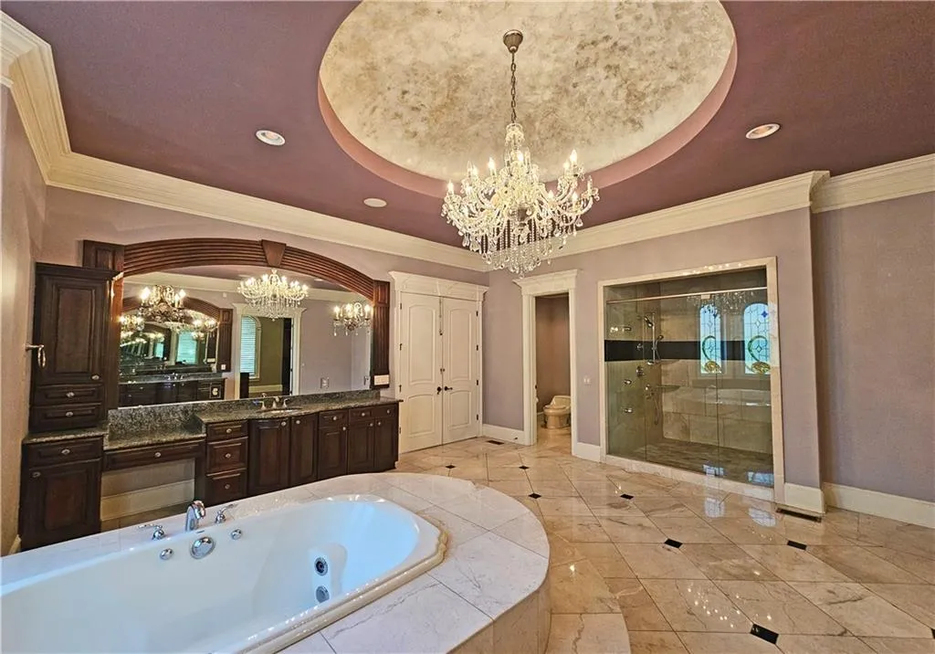 Bathroom featuring vanity, a raised ceiling, a notable chandelier, plus walk in shower, and tile flooring