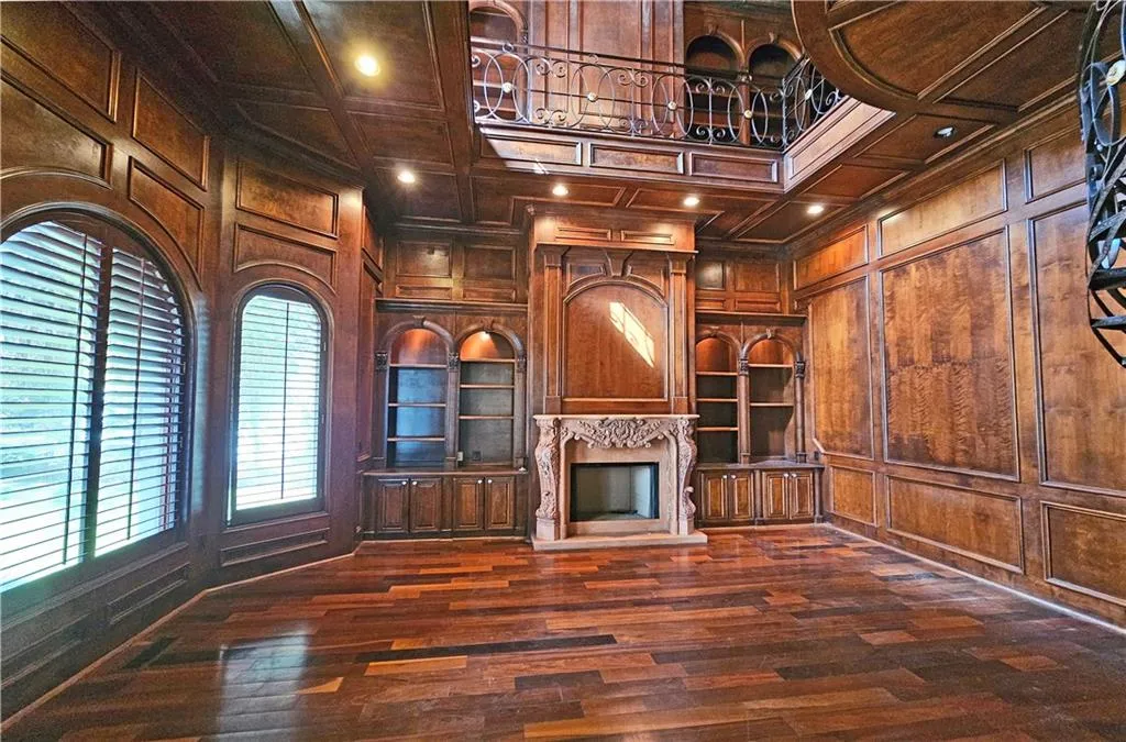 Unfurnished living room featuring coffered ceiling, wooden walls, a fireplace, and dark wood-type flooring