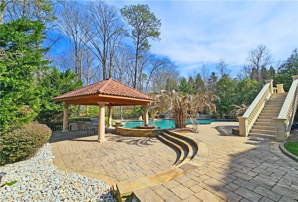 View of patio featuring a gazebo and a pool with hot tub