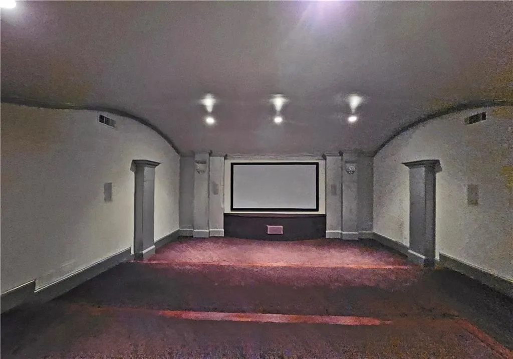 Home theater room featuring dark carpet and decorative columns