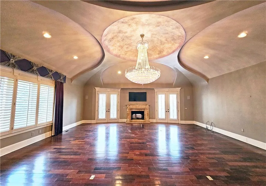 Unfurnished living room with an inviting chandelier, dark hardwood / wood-style flooring, and french doors