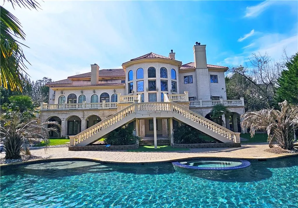 Rear view of property featuring a pool with hot tub and a balcony