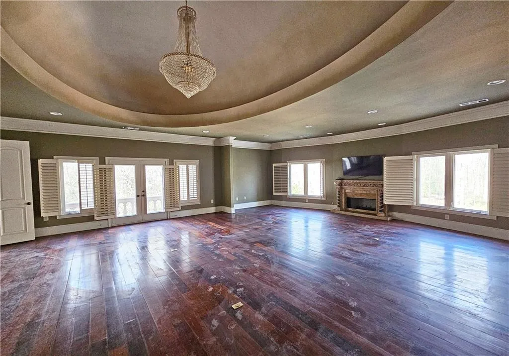 Unfurnished living room with dark hardwood / wood-style floors, ornamental molding, a tray ceiling, and french doors