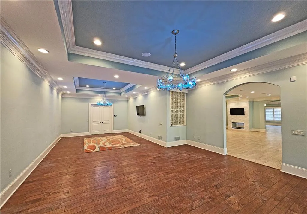 Empty room featuring a raised ceiling, ornamental molding, and hardwood / wood-style flooring