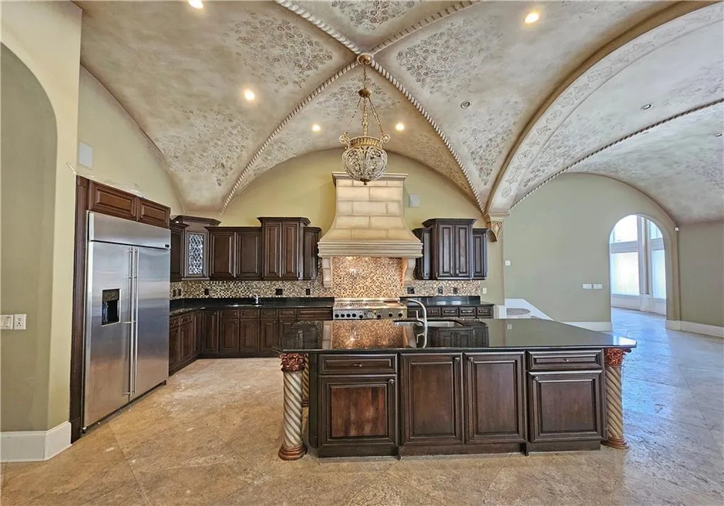 Kitchen featuring appliances with stainless steel finishes, an island with sink, tasteful backsplash, and custom range hood