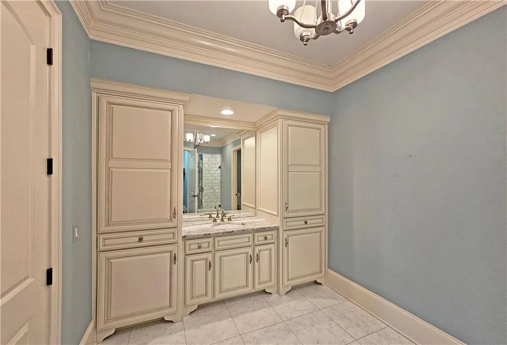 Bathroom featuring a notable chandelier, crown molding, tile floors, and vanity