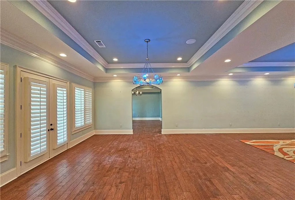 Spare room featuring dark wood-type flooring, french doors, crown molding, and a raised ceiling