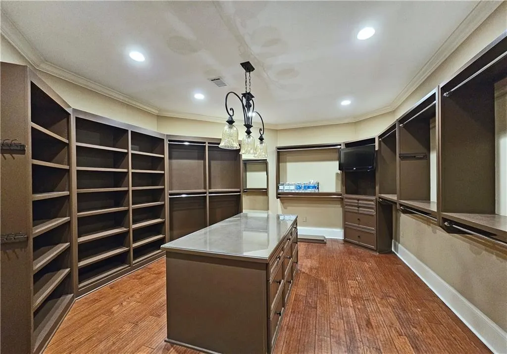 Walk in closet with hardwood / wood-style floors