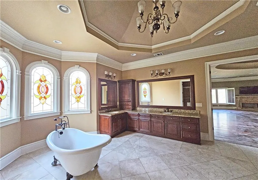 Bathroom with vanity, a raised ceiling, a tub, a chandelier, and tile flooring
