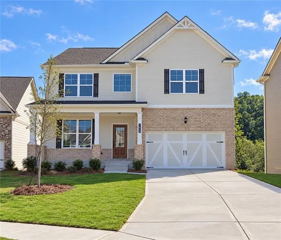 Quick Move In-Two-story residence featuring light-colored siding, a brick facade, and a covered front porch with white columns on a basement!