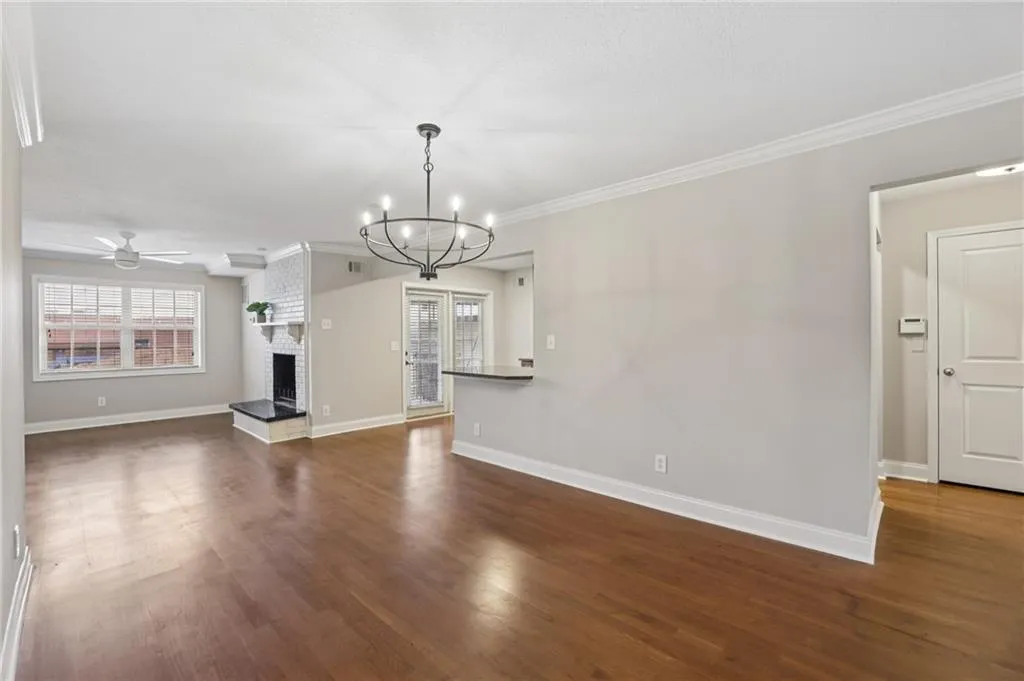 Unfurnished living room featuring ornamental molding, a fireplace, dark wood-type flooring, a chandelier, and ceiling fan