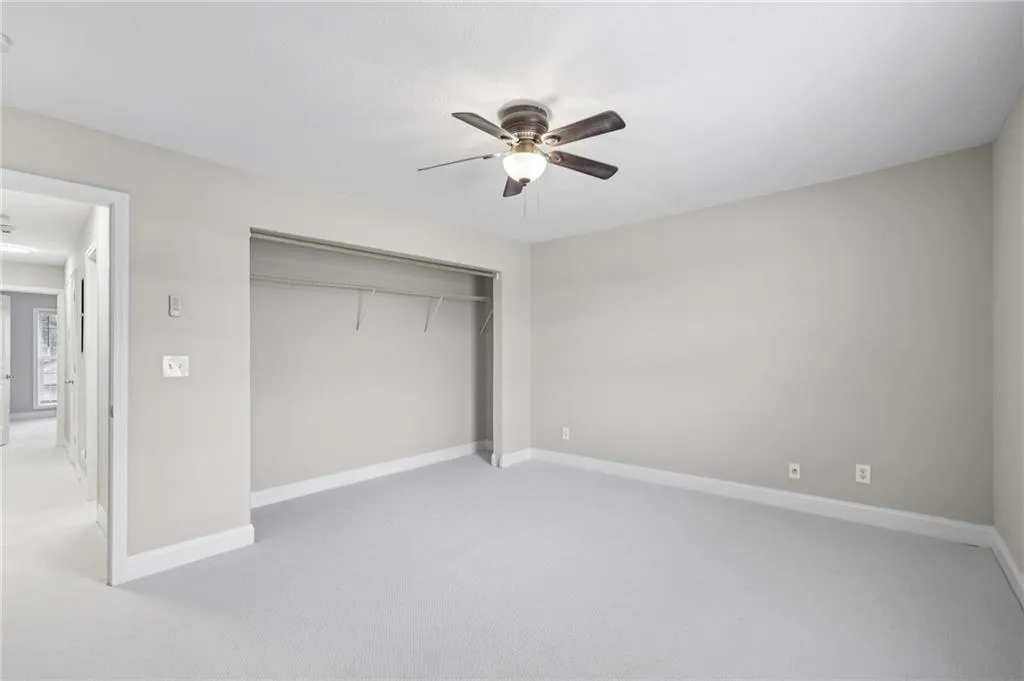 Unfurnished bedroom featuring light colored carpet, a closet, and a ceiling fan