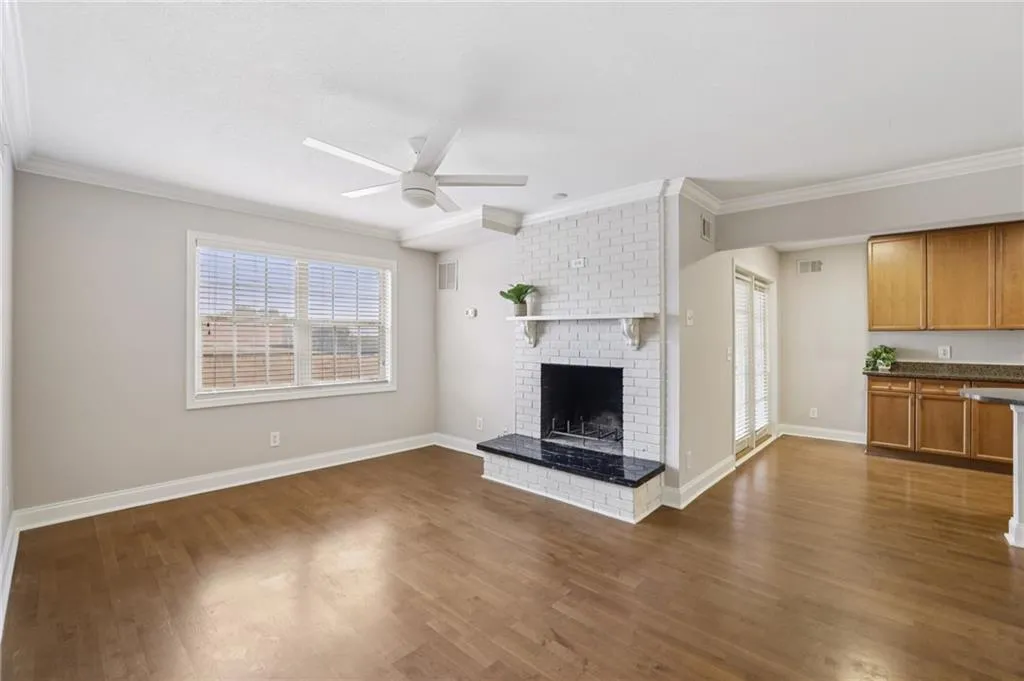 Unfurnished living room featuring ornamental molding, a fireplace, dark wood-style floors, and ceiling fan