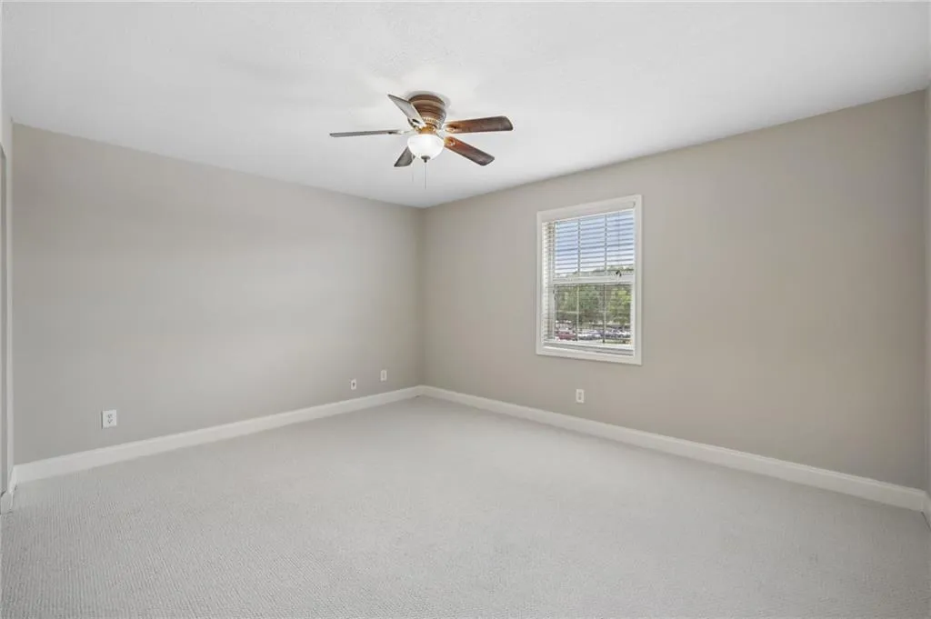 Unfurnished room featuring light carpet and a ceiling fan