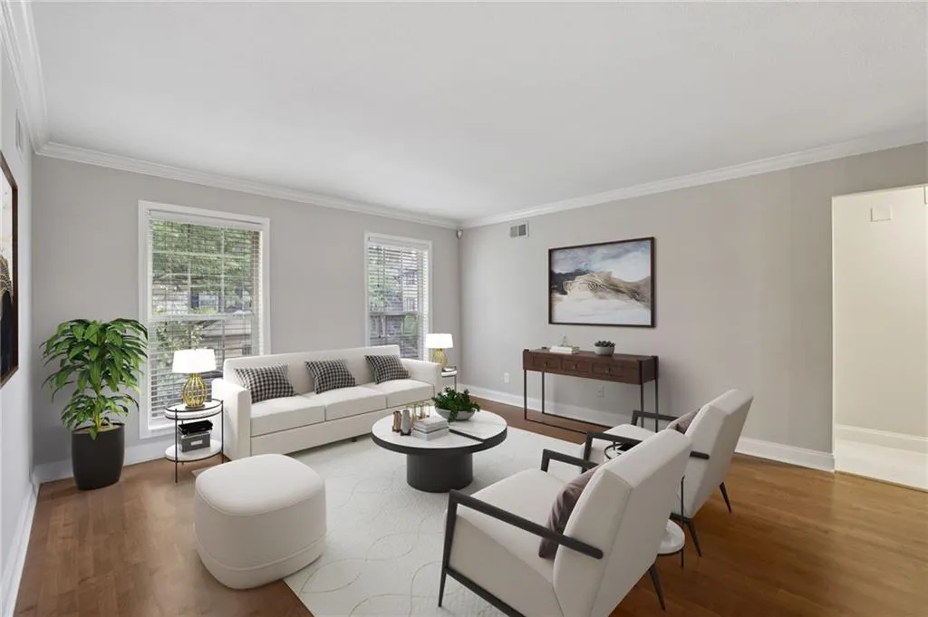 Digitally staged. Living area featuring wood finished floors and ornamental molding