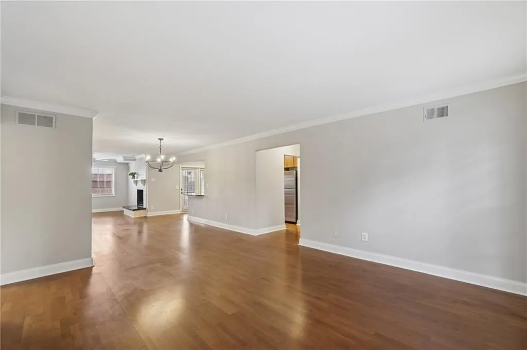 Unfurnished living room featuring ornamental molding, dark wood-style flooring, and a chandelier