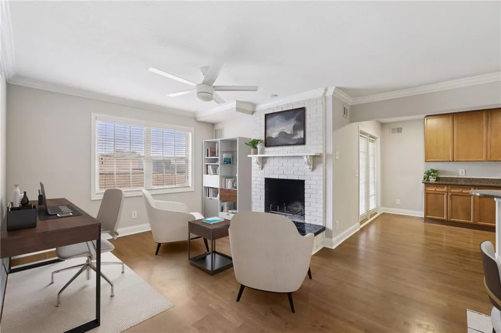 Digitally staged. Office space featuring ornamental molding, a fireplace, wood finished floors, and ceiling fan