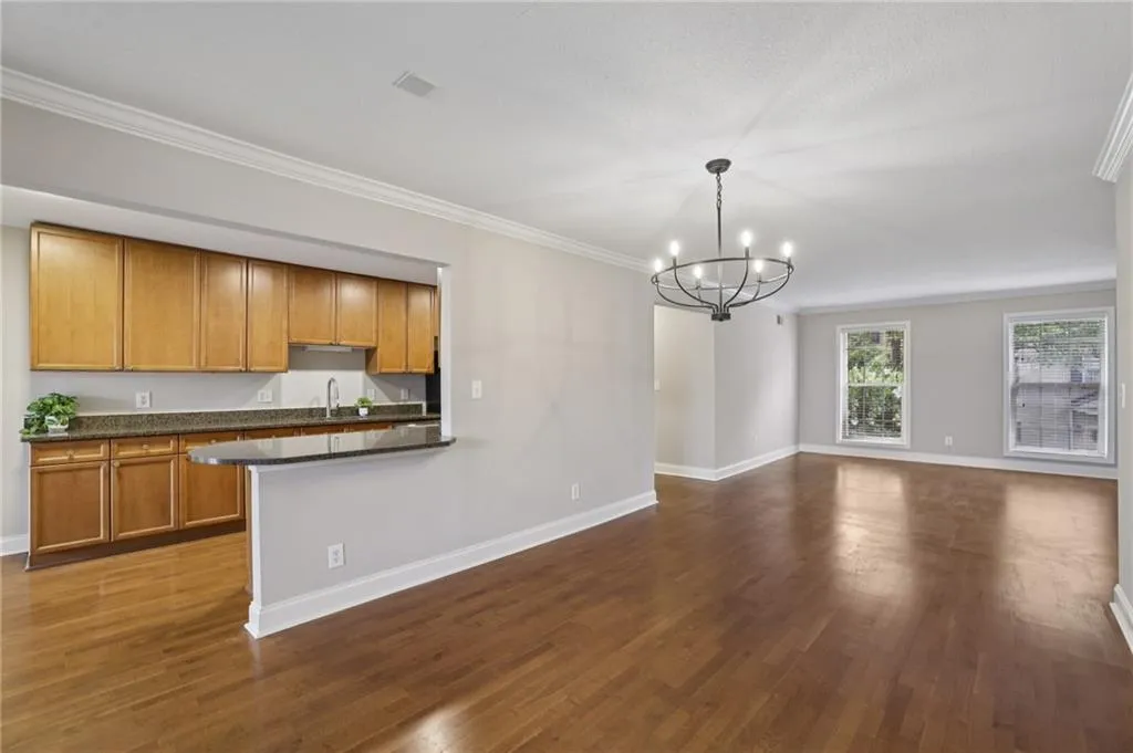 Kitchen with ornamental molding, dark countertops, dark wood-type flooring, a chandelier, and brown cabinets