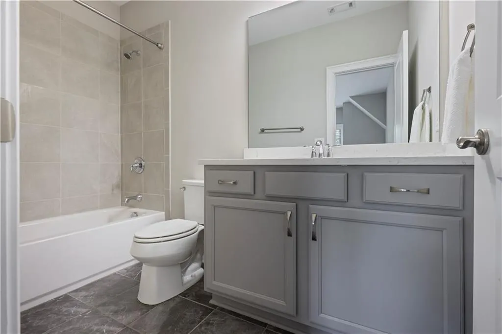 Full bathroom with tiled shower / bath combo, vanity, and toilet
