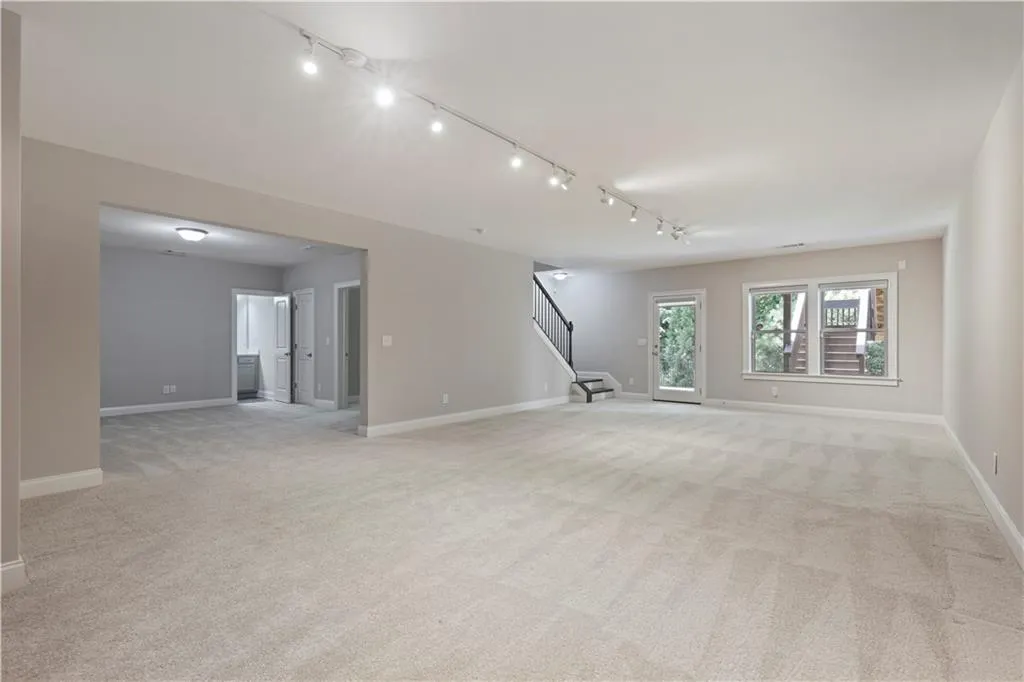 Carpeted spare room featuring track lighting