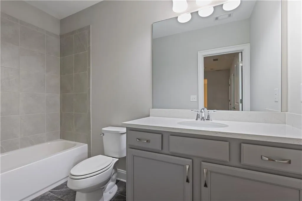 Full bathroom with tile patterned flooring, vanity, toilet, and tiled shower / bath combo