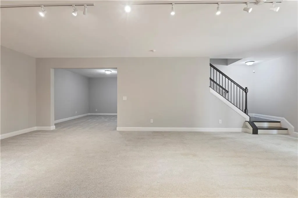 Unfurnished living room with light colored carpet and track lighting