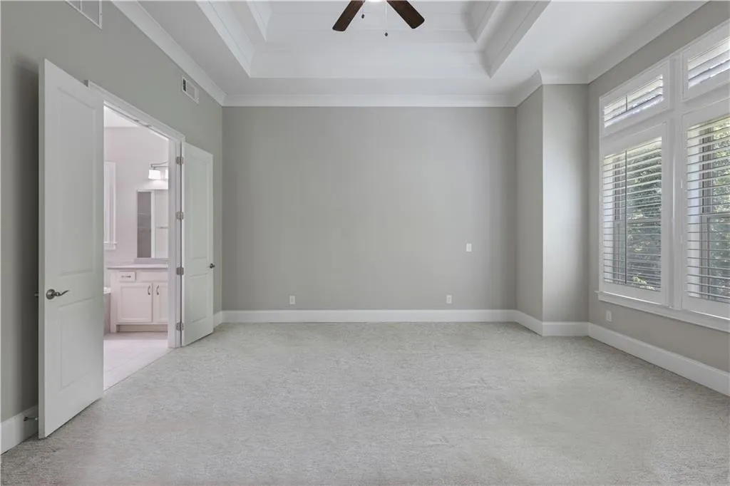 Spare room with light colored carpet, ceiling fan, ornamental molding, and a tray ceiling