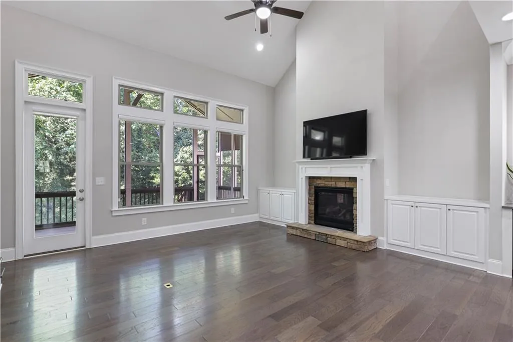 Unfurnished living room with ceiling fan, dark hardwood / wood-style floors, high vaulted ceiling, and a fireplace