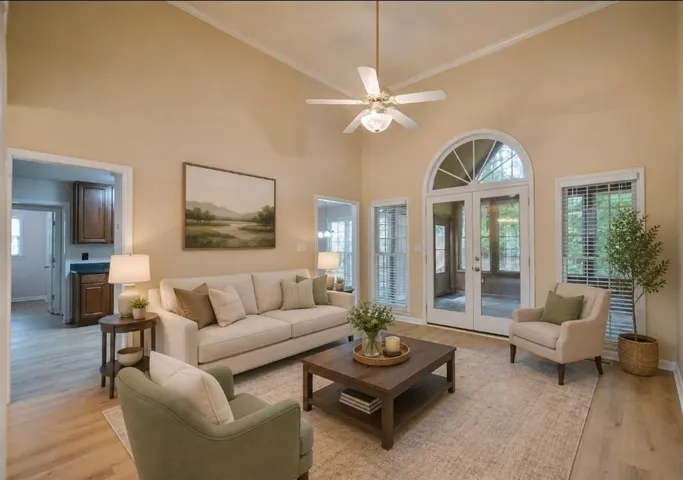 Vaulted ceiling living space featuring wood-finish flooring, a ceiling fan, and French doors with an arched transom