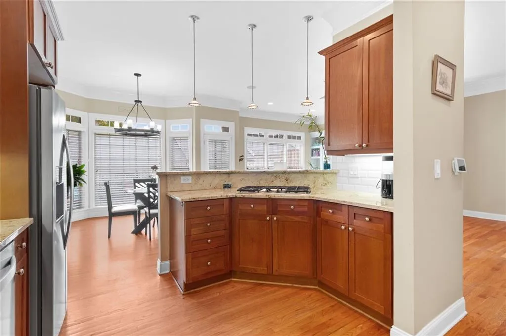Kitchen featuring crown molding, light stone countertops, light wood-type flooring, wood finish cabinetry, and a peninsula